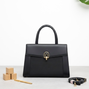 Elegant brown leather handbag with gold accents on modern desk - Onyx